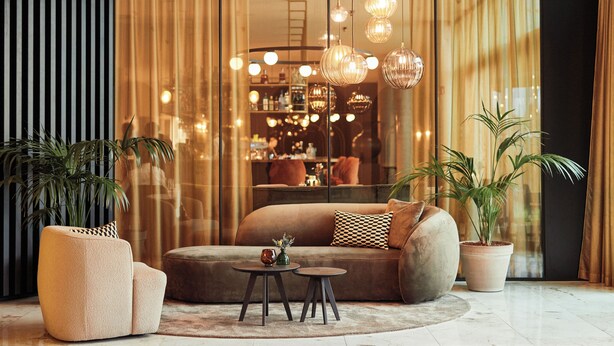 A modern living room with a sofa, two side tables, and hanging spherical light fixtures.