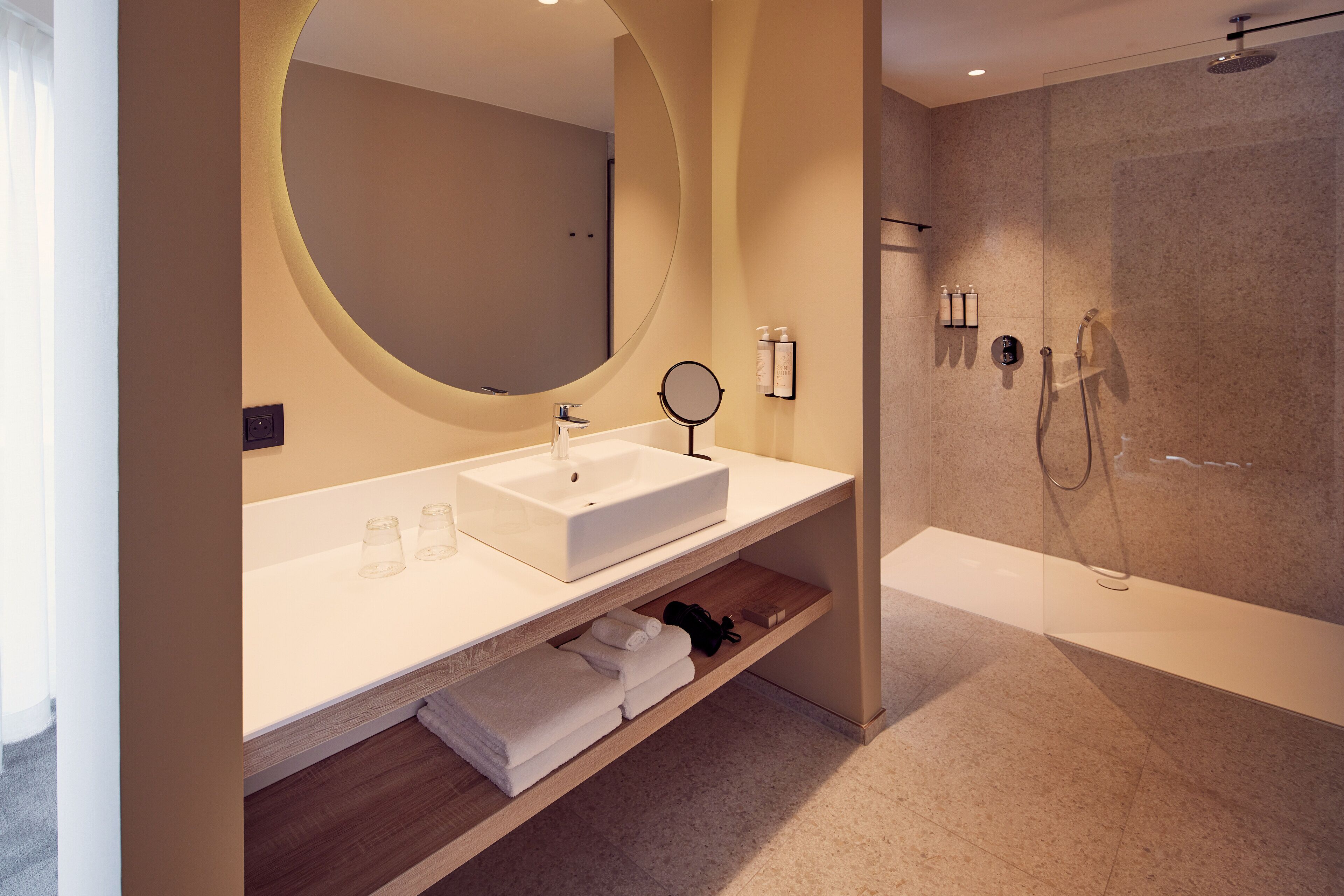 Een moderne badkamer met een grote spiegel, een wastafel en een douchehoek.
