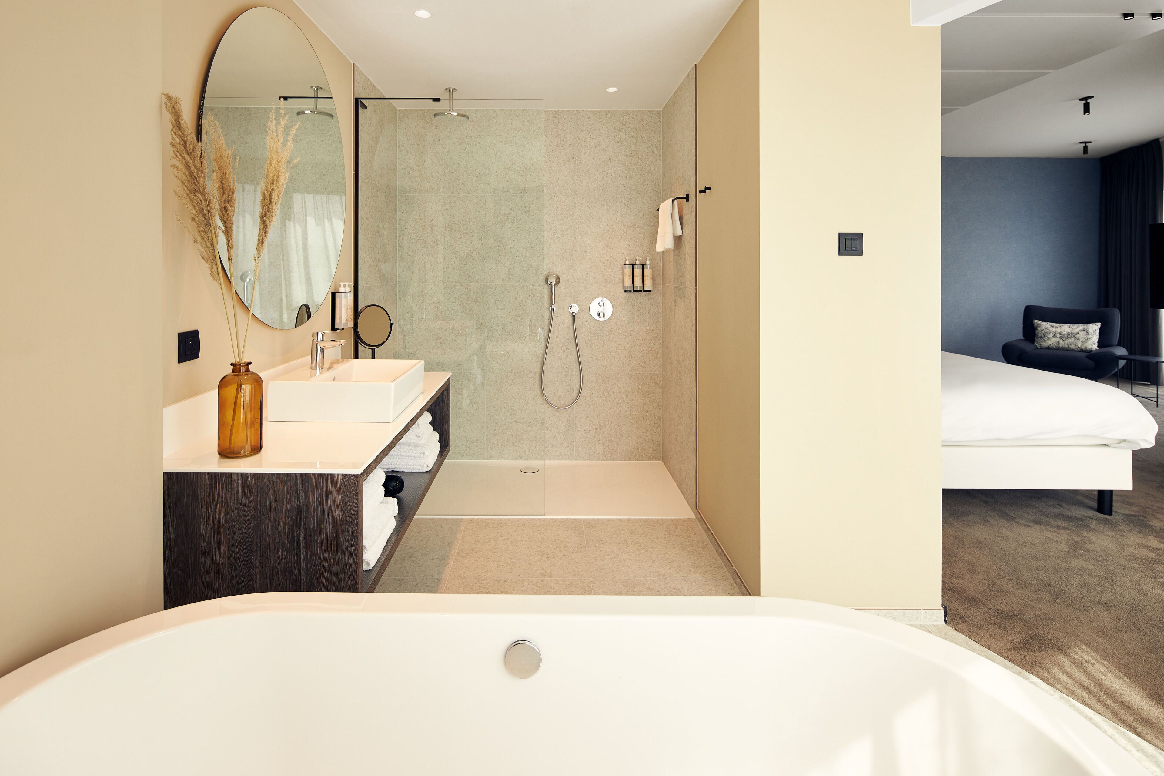 A modern bathroom with a bathtub, two sinks, a shower, and a large mirror.