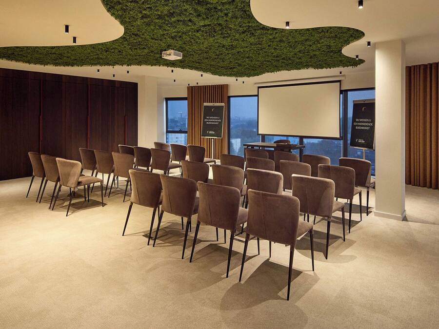 A conference room with a green ceiling, a large screen, and a view of the city.