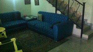 Un soggiorno con un divano blu decorato, un tavolino e una scala con ringhiera nera.