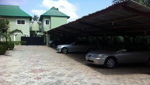 Una strada asfaltata che conduce a un portico coperto dove sono parcheggiate due auto.