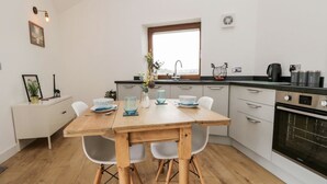 Eine moderne Küche mit einem Holztisch, weißen Stühlen, einem Fenster und einem eingebauten Backofen.
