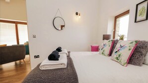 Ein modernes Schlafzimmer mit einem großen Bett, einem Nachttisch, einem Spiegel und einem Fenster.