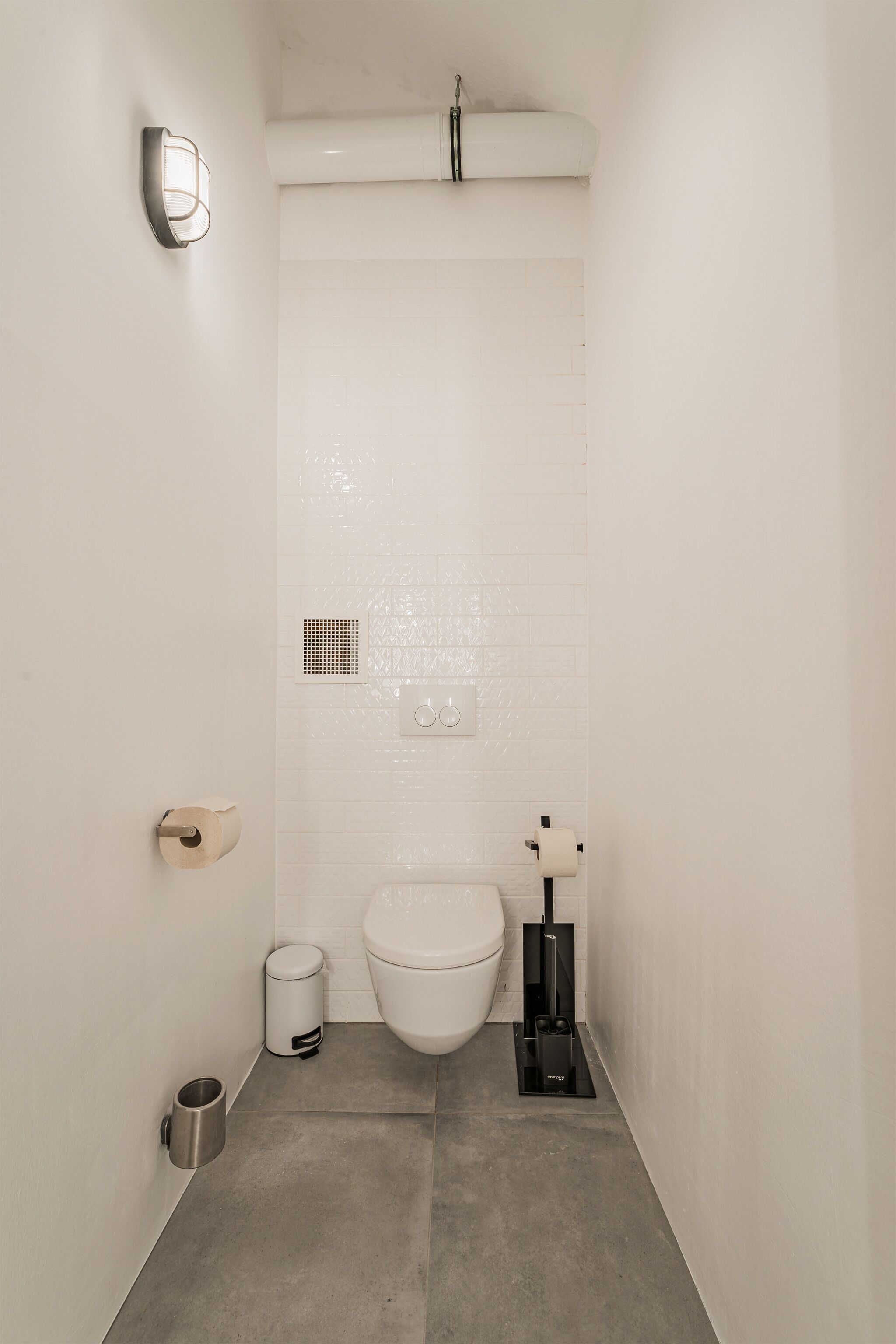 Une petite salle de bain moderne équipée de toilettes, d’un bidet et d’une poubelle.