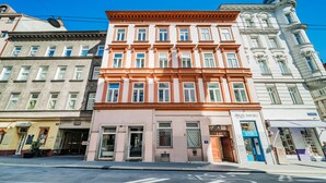 A multi-story building with a pink facade and large windows. - easy-flat Neustiftgasse - AC Studio Apartments near MuseumsQuartier (Vienna)