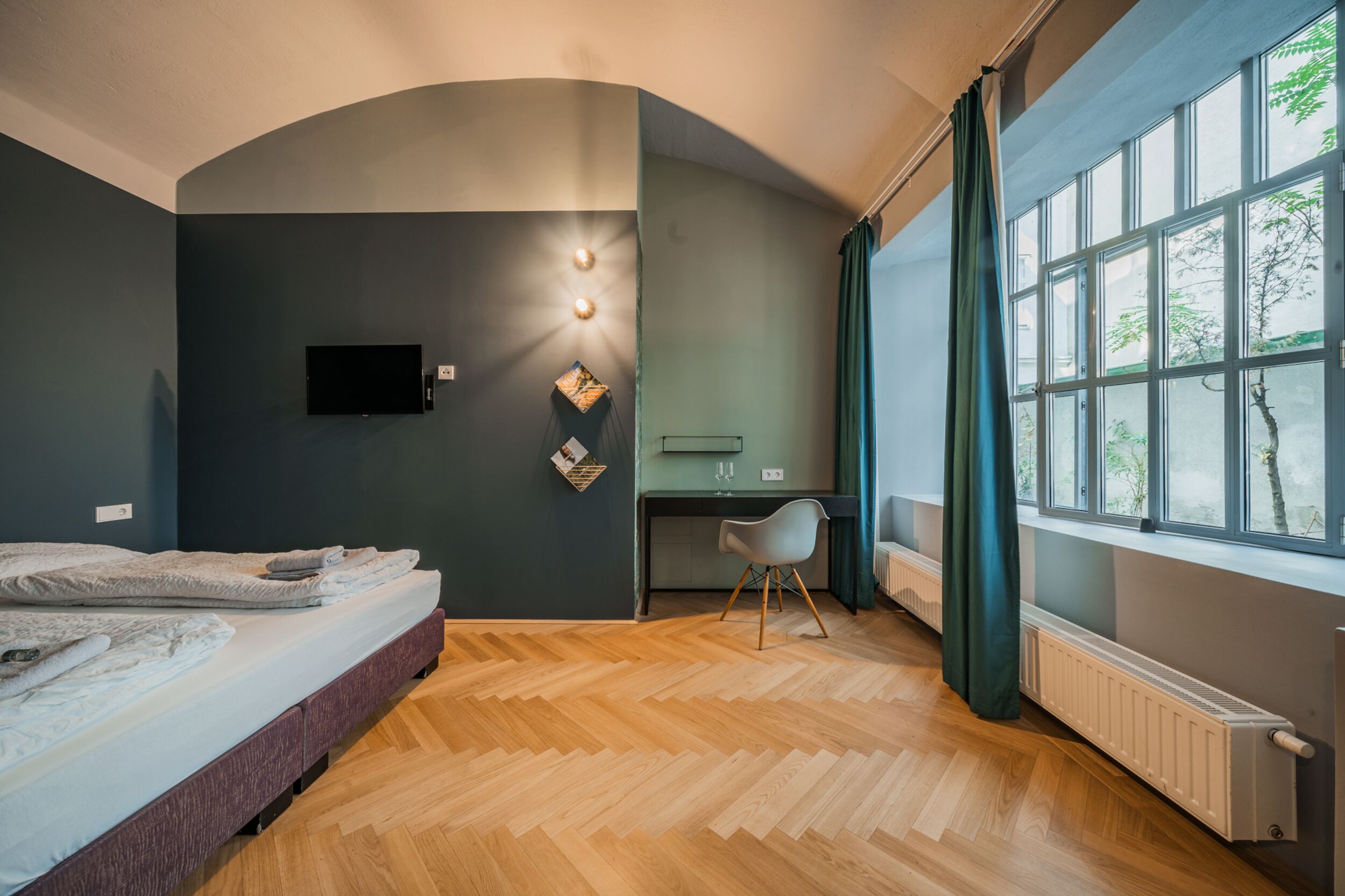 Een moderne slaapkamer met een bed, bureau en groot raam.