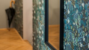 A bathroom with a wooden floor, a mirror, and a wall with a floral pattern. - easy-flat Neustiftgasse - AC Studio Apartments near MuseumsQuartier (Vienna)