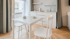 A modern kitchen with white cabinets, a dining table with chairs, and a pendant light. - easy-flat Neustiftgasse - AC Studio Apartments near MuseumsQuartier (Vienna)