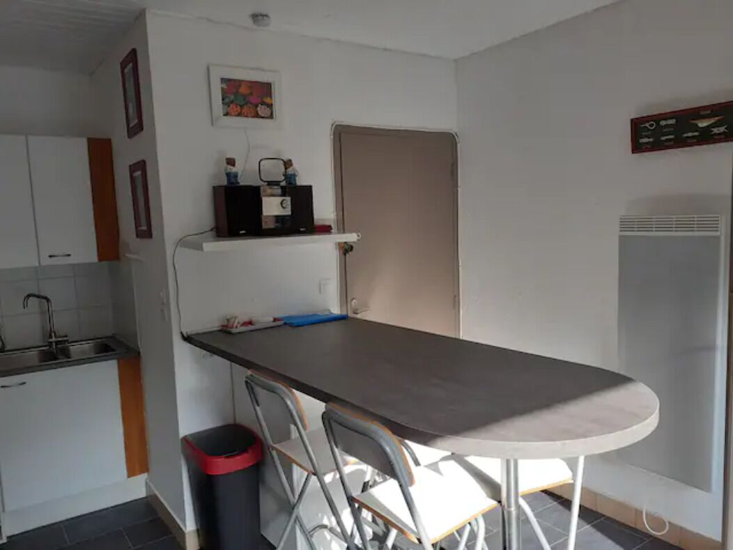 Eine kleine Küche mit Esstisch, Stühlen, Spüle und Kühlschrank.