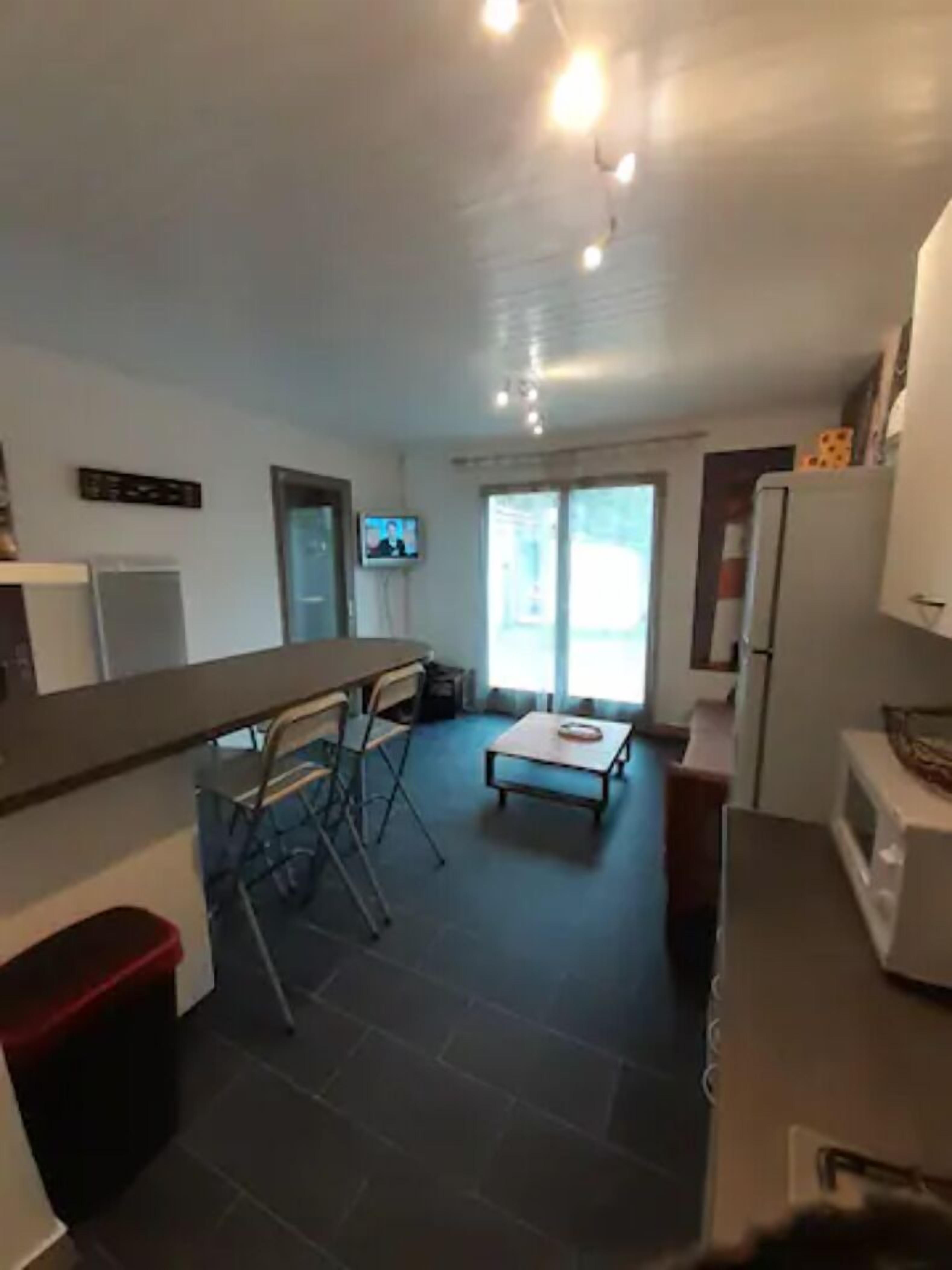 Una cocina compacta con comedor, televisor y refrigerador.