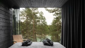 A room with a bed, a chair, and a view of a forest. - The Baro (Inga)