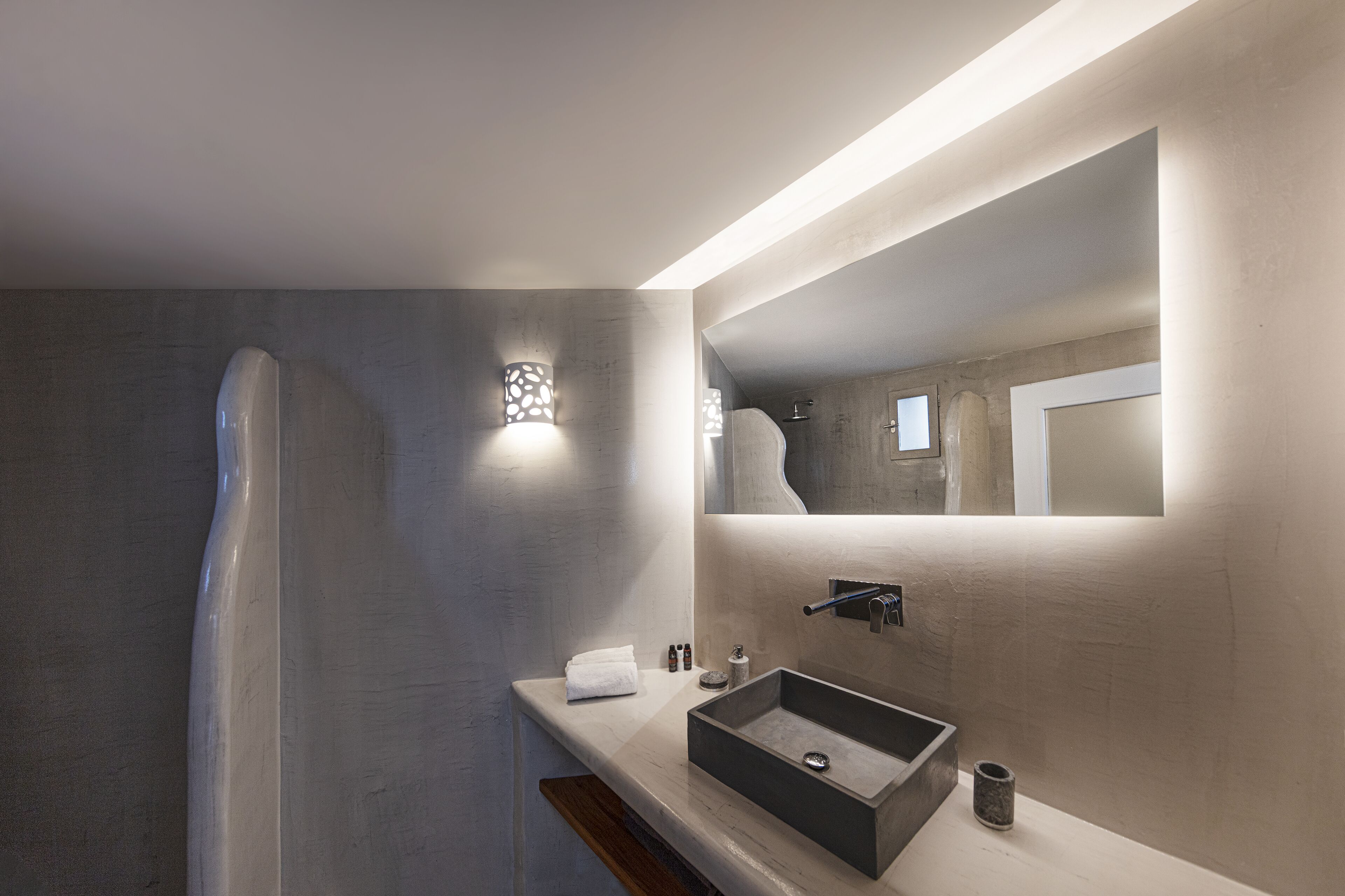 Un baño moderno con un lavabo rectangular, un espejo grande y una ducha.