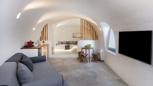 Una sala de estar moderna con un sofá, un comedor con una mesa y sillas, y una zona de cocina con mostrador y electrodomésticos.