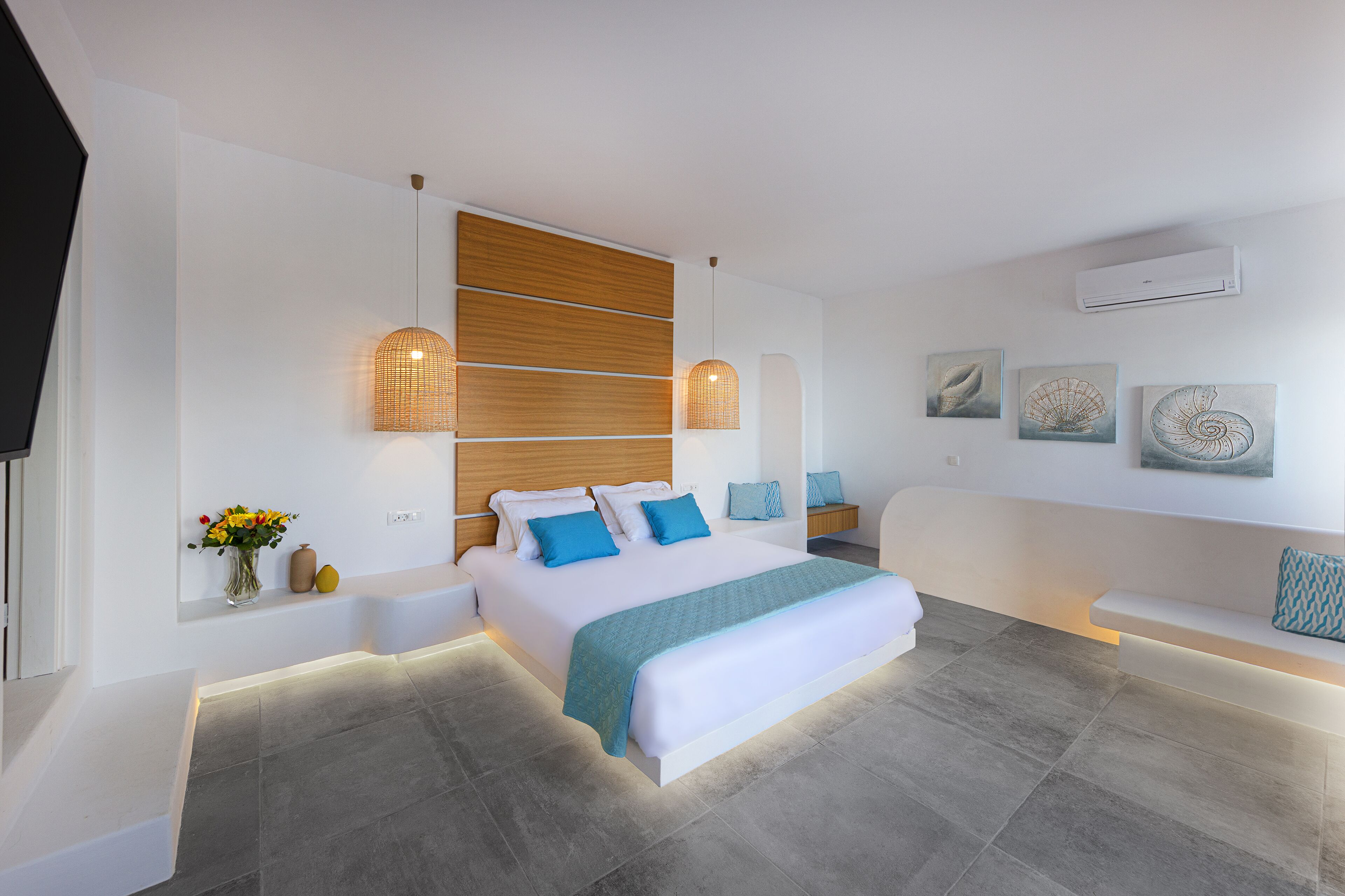 Una camera da letto moderna con un grande letto, comodini, una panca integrata e opere d'arte appese al muro.