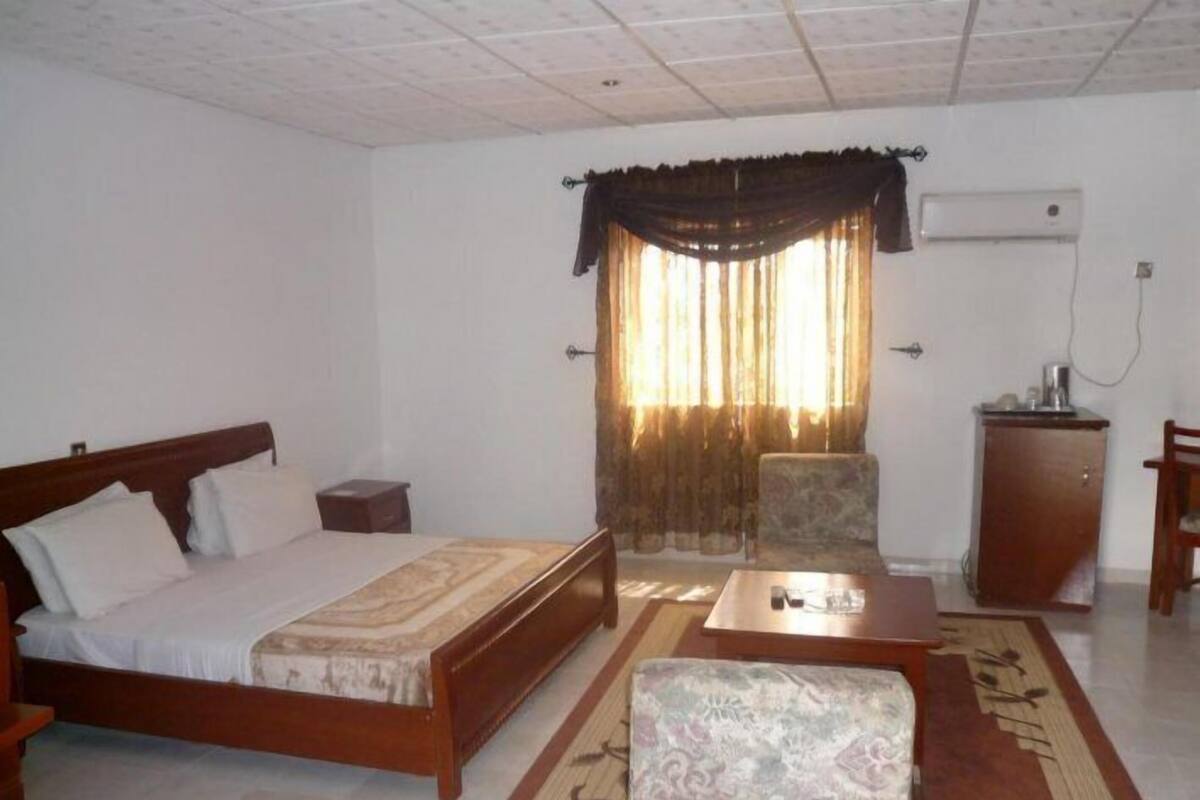 Una habitación con una cama, una mesita, una silla y un escritorio.