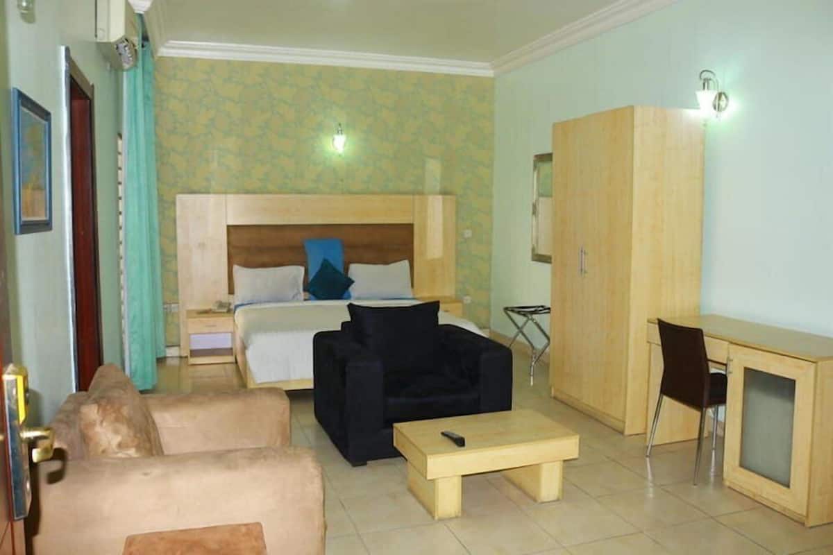 Una habitación con cama, sofá, escritorio y armario.