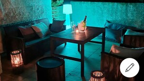 Un espace extérieur aménagé avec une table, des chaises et une bouteille de champagne.