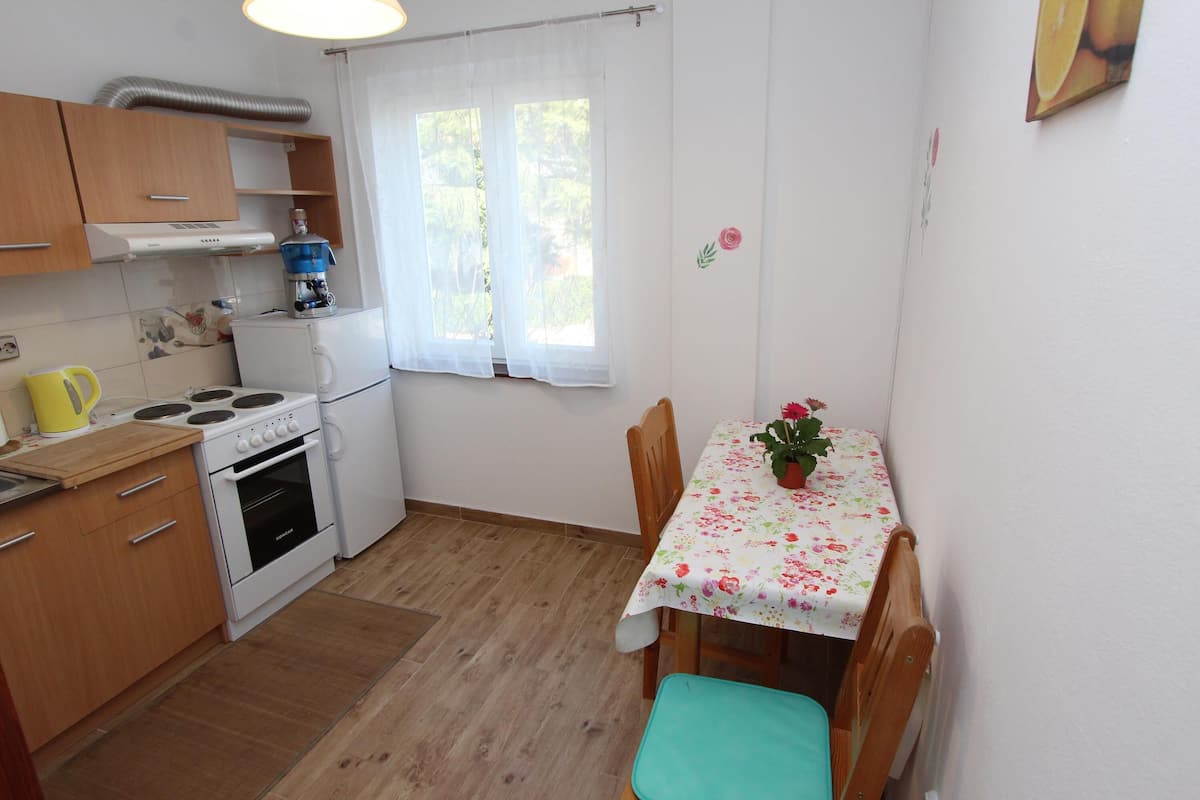A compact kitchen with wooden cabinets, a stove, and a table with a floral tablecloth.