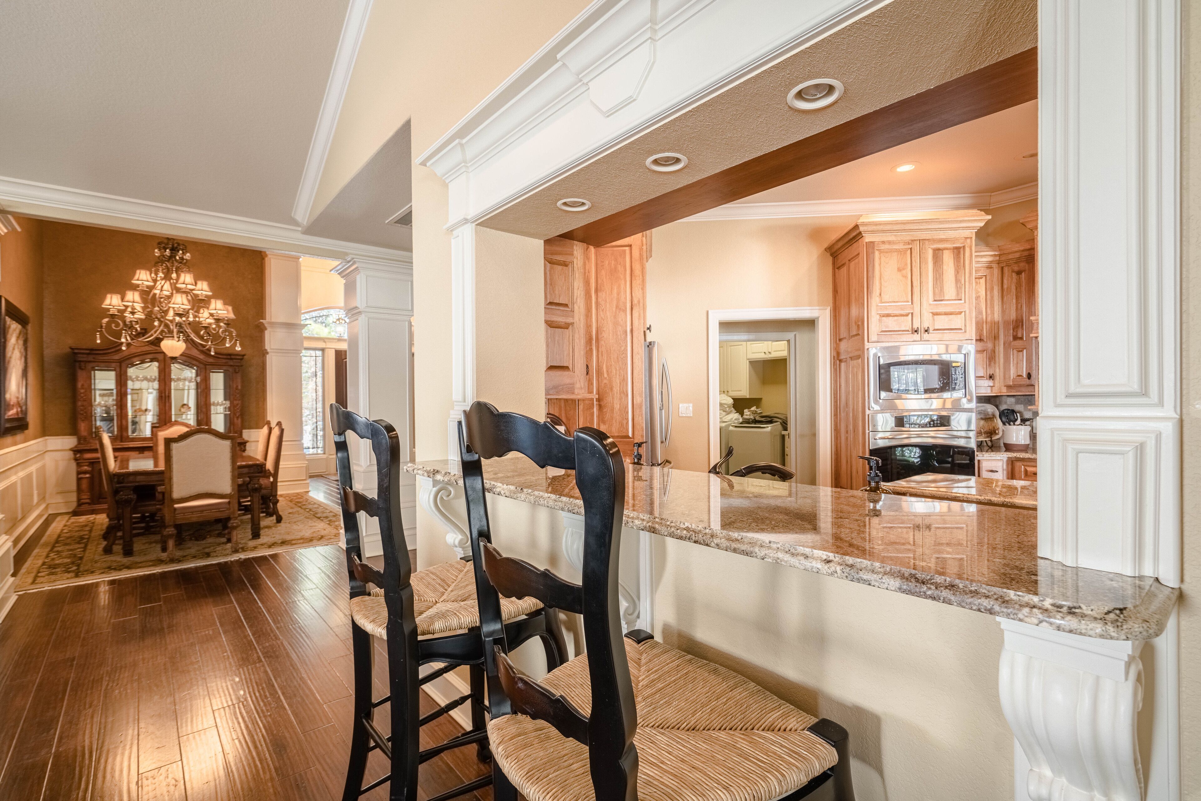 A spacious kitchen with granite countertops, wooden cabinets, and a built-in microwave.