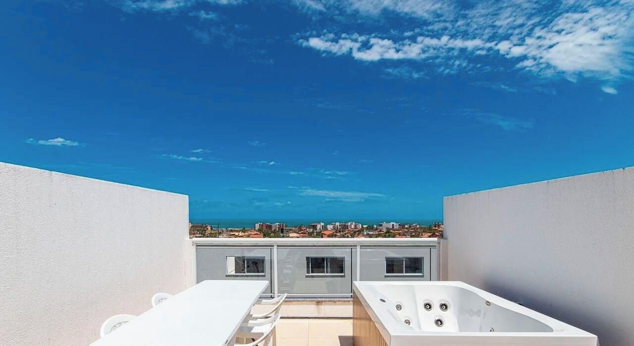 Una terraza en la azotea con vistas a la ciudad, una bañera de hidromasaje y un espacio de estar.