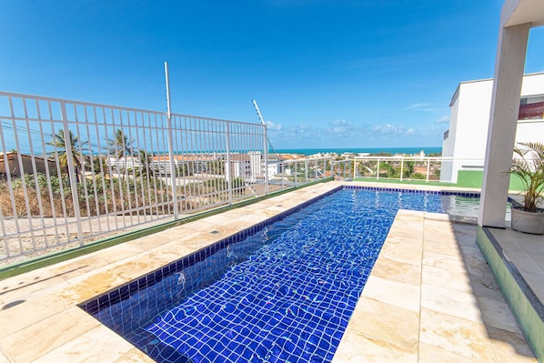 Una piscina con vista al océano, rodeada por una valla y un edificio.