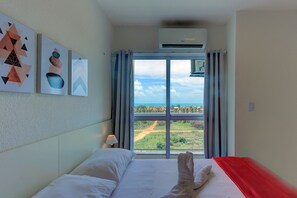 A hotel room with a bed, a window with curtains, and three wall-mounted artworks. - Triplex Hidromassagem em Porto das Dunas (Aquiraz)