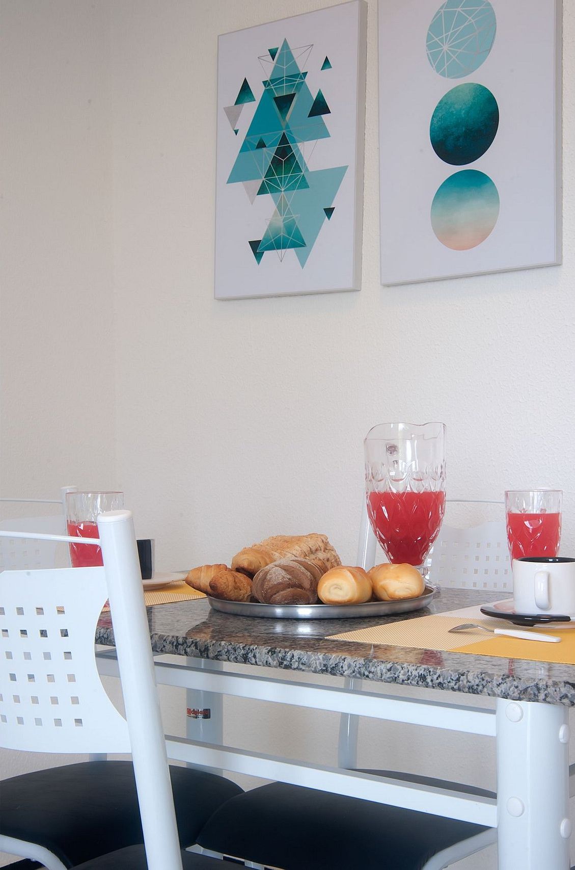 A breakfast setup with pastries, a glass pitcher, and two glasses of red beverage on a table.