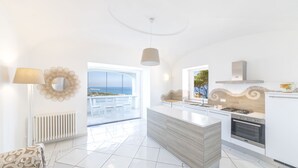 Eine moderne Küche mit einer großen Kochinsel, Meerblick und einem Balkon.