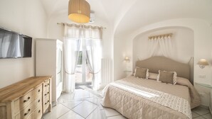 Ein Schlafzimmer mit einem großen Bett, einer hölzernen Kommode, einem Fernseher und einer Deckenleuchte.