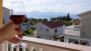 Una mano sosteniendo una copa de vino, con vistas a un pueblo costero.
