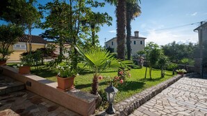 Un jardín con plantas en macetas, un camino de piedra y un edificio al fondo.