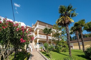 Ein mehrstöckiges Hotel mit einer zentralen Treppe, umgeben von üppiger Vegetation und Palmen.