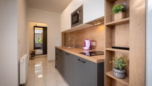 A modern kitchen with a built-in microwave, a kettle, and wooden shelves with potted plants. - Apartment Šerbečić 4 with sea view for 4 persons on the island of Krk (Malinska)