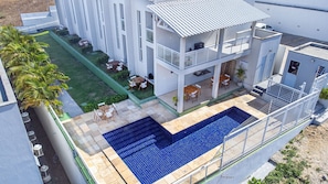 Un bâtiment à deux étages doté d’une piscine, d’un espace extérieur aménagé et d’une pelouse bien entretenue.