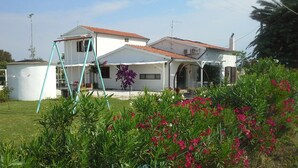 Ein weißes Haus mit rotem Ziegeldach, einer überdachten Terrasse und einer Schaukel.