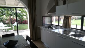 Eine moderne Küche mit Gasherd, Spüle und großen Fenstern mit Blick auf einen Garten.