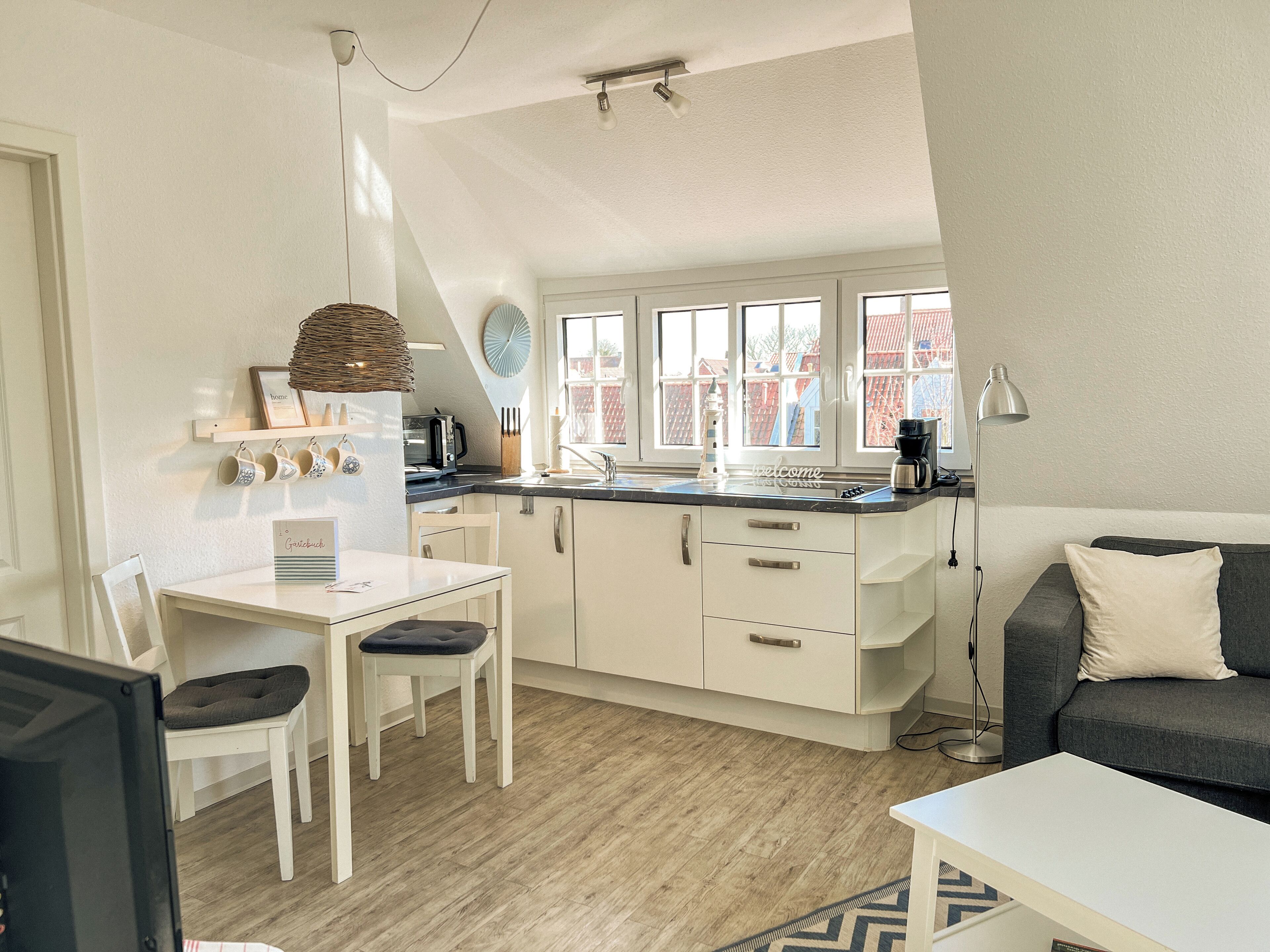 A compact kitchen with a dining area, a sofa, and a lamp.