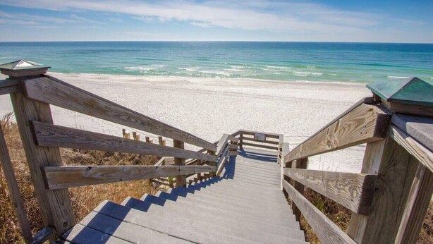 A wooden staircase leading to a beach with clear blue water.