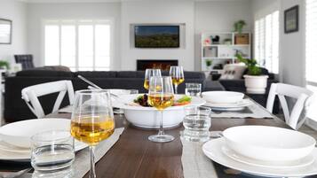 Comedor con una mesa de madera para cuatro, copas de vino blanco y un bol de ensalada.
