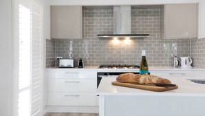 A modern kitchen with white cabinets, a gas stove, a toaster, and a loaf of bread on the counter. - The Bunkhouse - quality, contemporary home (Exeter)