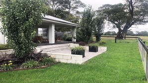 A modern house with a covered patio, outdoor seating, and a well-maintained garden. - The Bunkhouse - quality, contemporary home (Exeter)