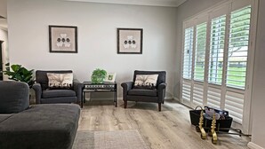 A living room with two armchairs, a coffee table, and a large window with blinds. - The Bunkhouse - quality, contemporary home (Exeter)