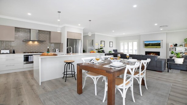 A modern kitchen with white cabinetry, a central island, and a dining area with a wooden table and white chairs. - The Bunkhouse - quality, contemporary home (Exeter)