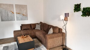 Een moderne woonkamer met een hoekbank, een houten salontafel, een vloerlamp en abstracte wanddecoratie.