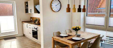 A modern kitchen with a dining area, a clock, and a view of the outside.