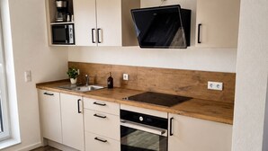Een moderne keuken met witte kasten, een houten aanrecht, een ingebouwde oven en een magnetron.