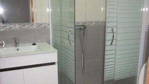 A modern bathroom with a glass-enclosed shower, a sink with a mirror, and a toilet. - Apartment A  Rosy Apartments (Madeira)