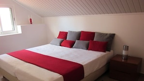 A bedroom with a bed, a nightstand, a lamp, and a window. - Apartment A  Rosy Apartments (Madeira)