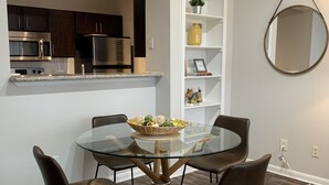 Una cocina moderna con armarios oscuros, electrodomésticos de acero inoxidable y encimera blanca.